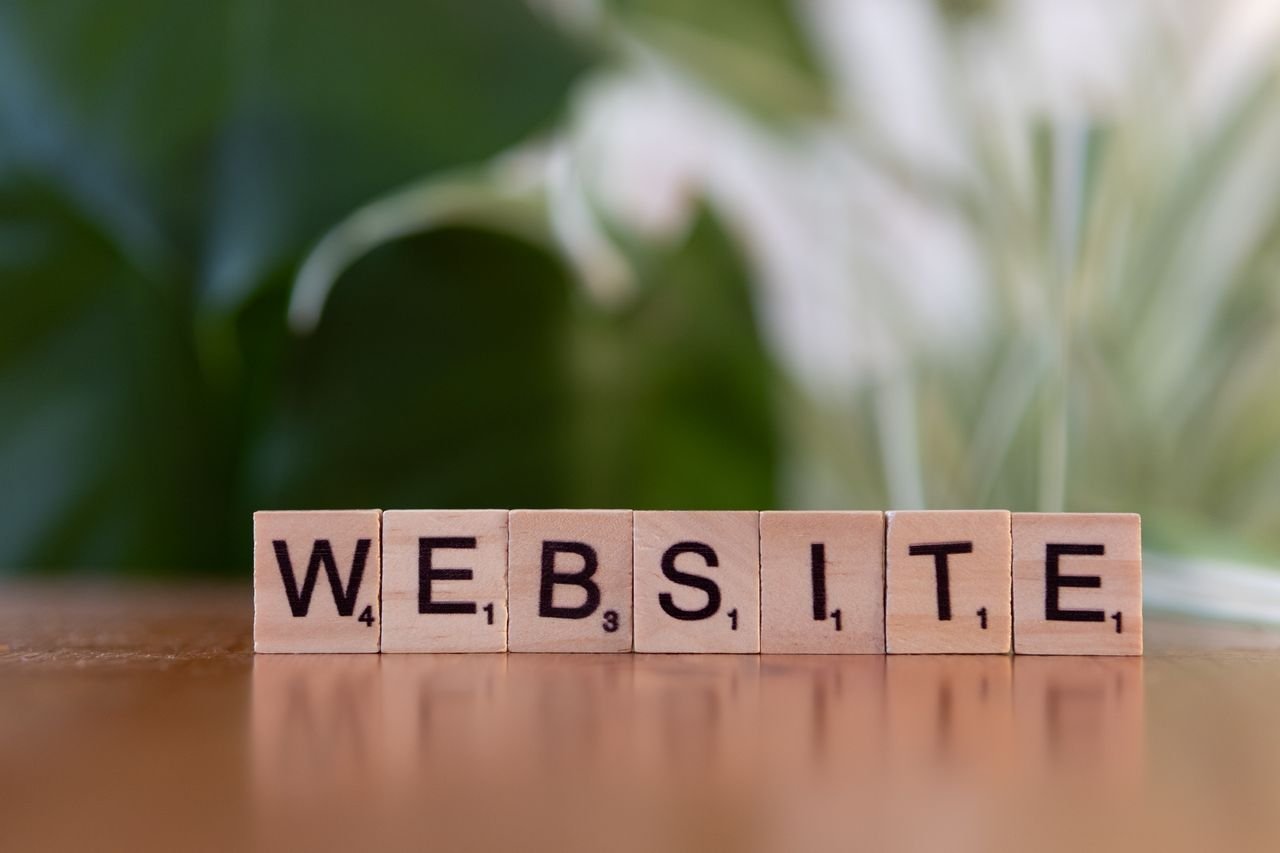 The Art of Drawing Readers In: Your attractive post title goes here Scrabble tiles on a wooden surface forming the word 'Website', symbolizing digital communication.